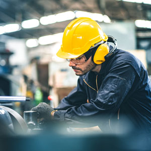 Ouvrier dans un environnement de travail industriel, portant des équipements de protection individuelle afin de réduire son exposition au bruit