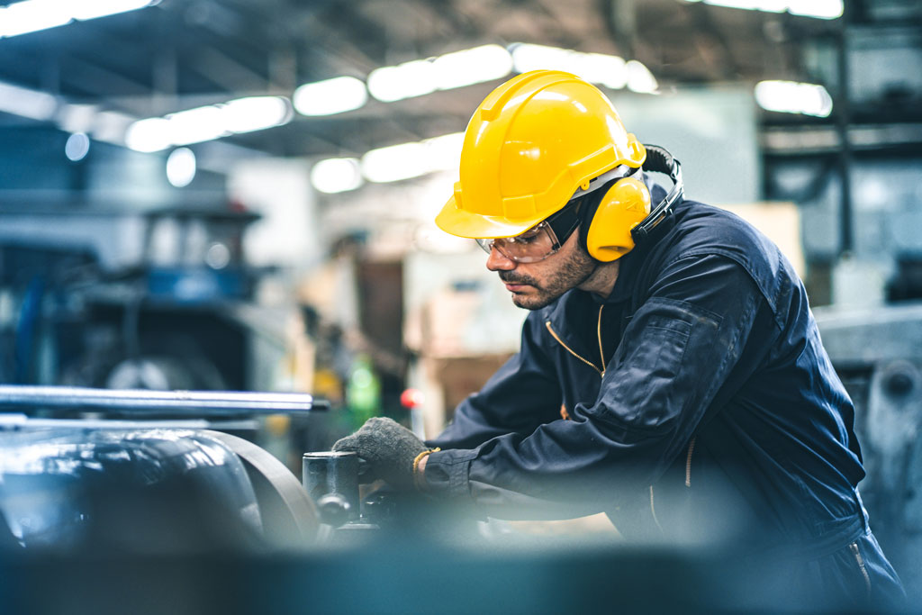 Ouvrier dans un environnement de travail industriel, portant des EPI afin de réduire son exposition au bruit